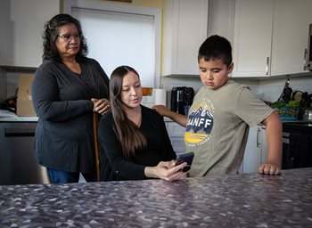 Une famille regarde le téléphone que tient la maman dans ses mains