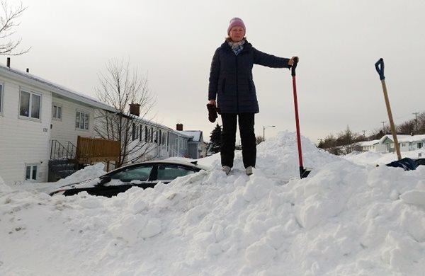 Saint John, Terre-Neuve-et-Labrador : Olga Kudryakova se tient sur un banc de neige imposant après la formidable tempête de neige surnommée Snowmaggedon.