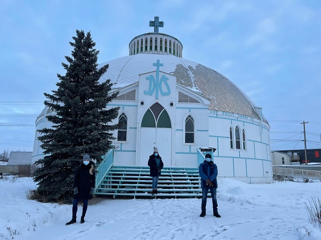 Three people outside a church in winter