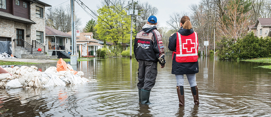 Inondations à Laval, en mai 2017. Deux personnes se tiennent dans l’eau et regardent les maisons.