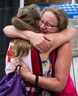 Un bénévole de la Croix-Rouge canadienne embrasse une femme dans un refuge