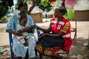 Une personne de la Croix-Rouge du Soudan du Sud discute avec une femme tenant un bébé.