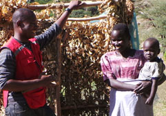Eunice Kisang (bénéficiaire) et Dancan Odero (agent, Approvisionnement en eau et assainissement, Croix-Rouge du Kenya) à côté d’une nouvelle latrine avec dalle. 