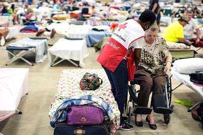 Une bénévole de la Croix-Rouge américaine aide une dame en chaise roulante