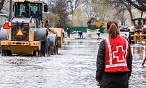 A Red Cross volunteer stands in a flooded street