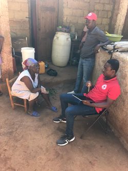 Deux membres de la Croix-Rouge discute avec une femme assise