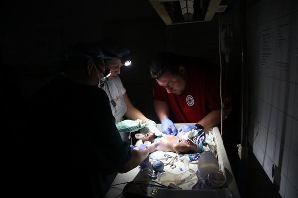 L’infirmier canadien Patrick Raymond pose une perfusion sur un nouveau-né à l’hôpital de district de Nhamatanda pendant une panne de courant.
