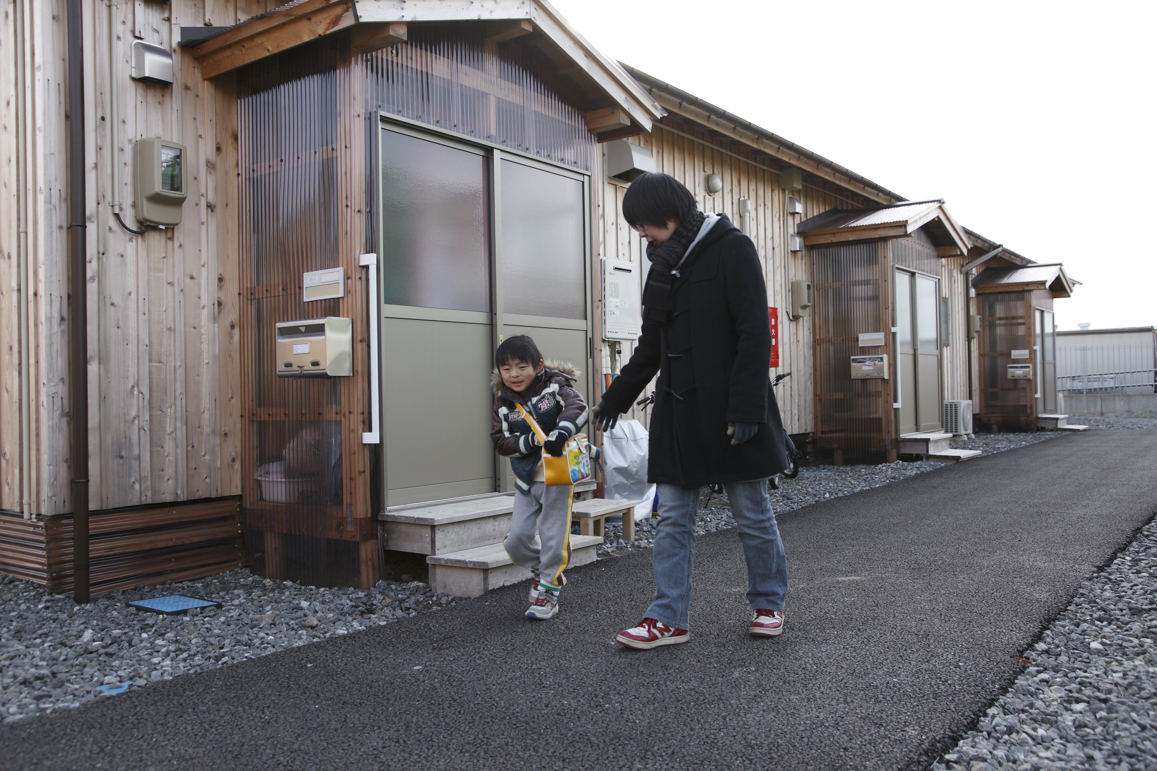 Takahito Ito, un jeune garçon de 5 ans, en compagnie de sa mère, Junko, devant leur logement temporaire dans la ville d’Iwaki. Takahito est l’un des enfants du village de Nahara qui fréquentent maintenant la maternelle temporaire. Sa mère affirme qu’il est toujours content de monter à bord de l’autobus le matin et qu’il aime beaucoup son école.