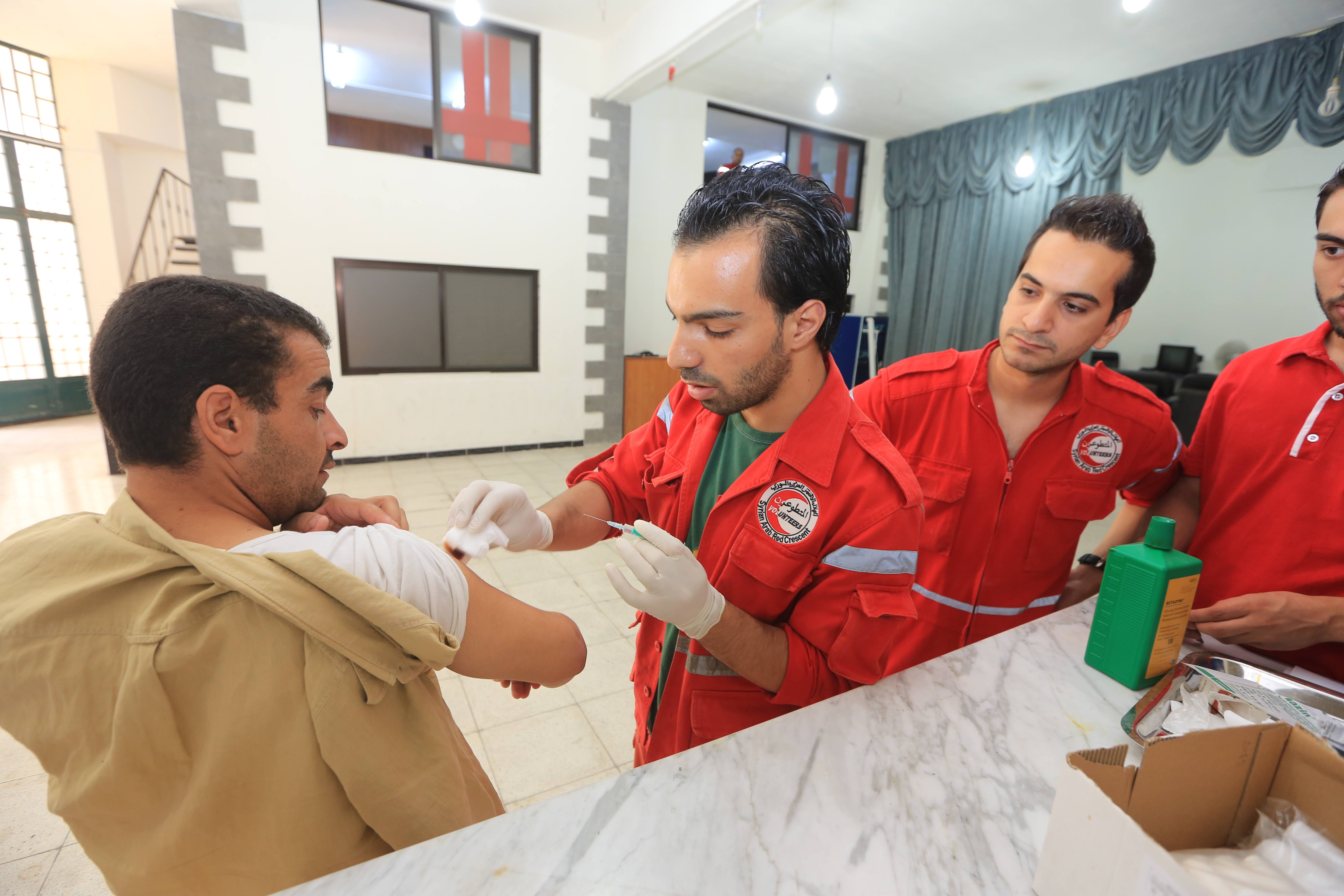 Un bénévole traite un patient à l'urgence de la polyclinique de Jaramana.  