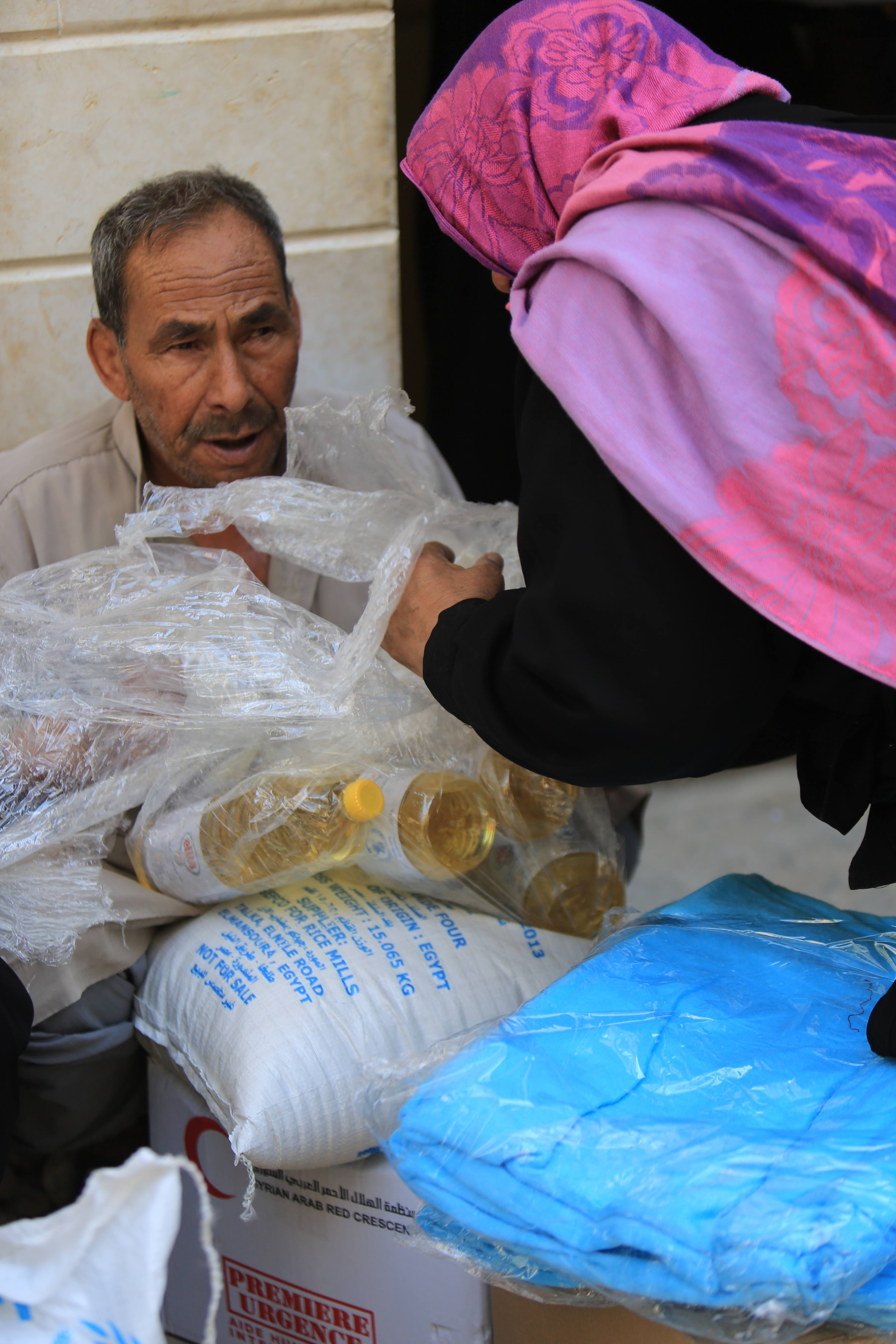 Un couple syrien recevant de la nourriture du Croissant Rouge arabe syrien. 
