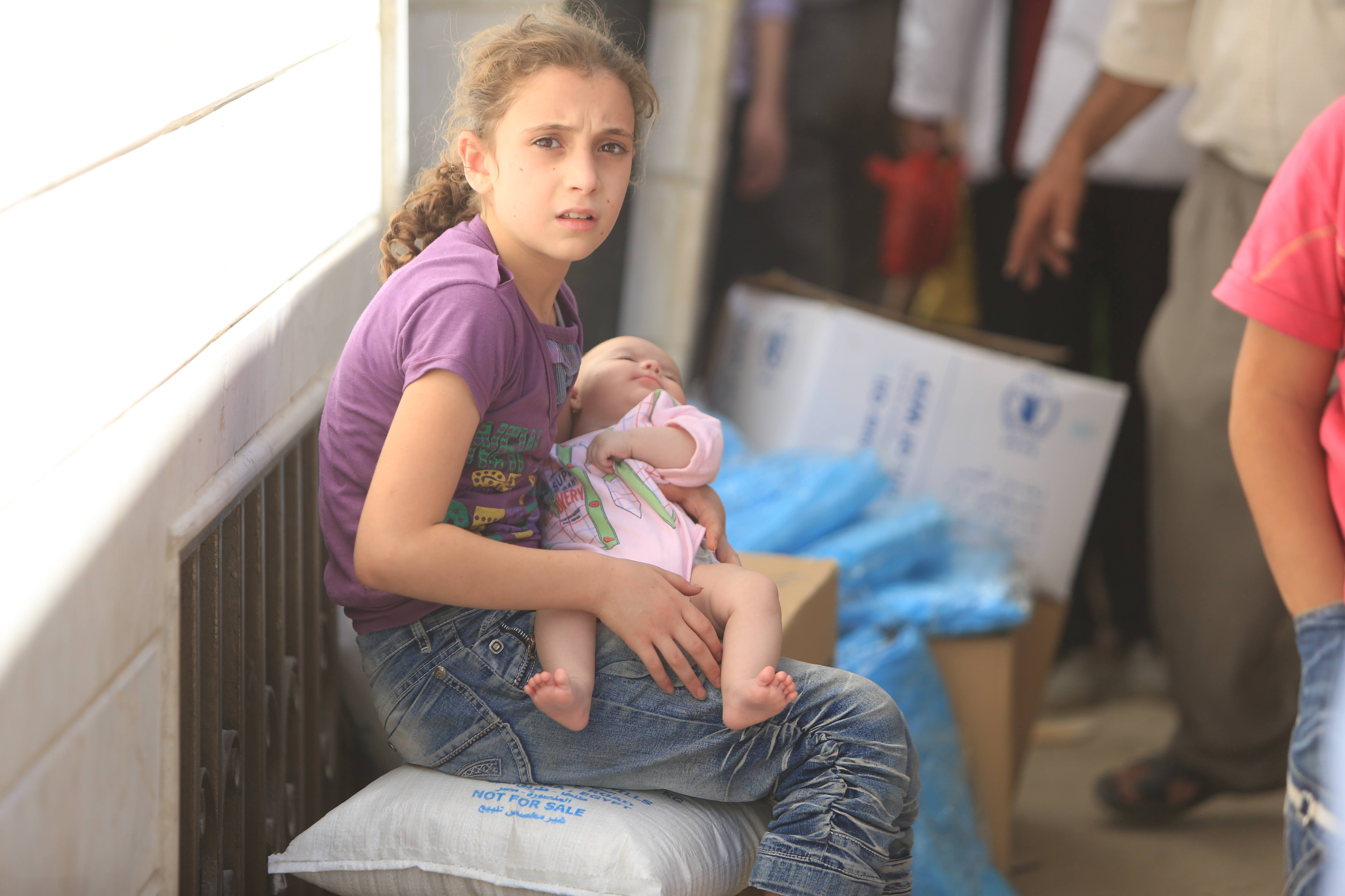 Une jeune syrienne et sa soeur attendent leur  portion de nourriture au centre de distribution de Jaramana. 