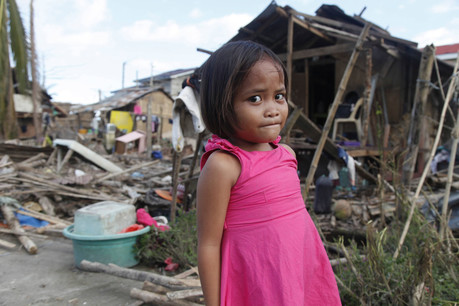 A little girl stands in a damaged area after Typhoon Haiyan