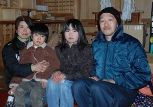 Une famille japonaise assise sur un divan regarde la caméra.