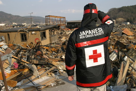A Japanese Red Cross worker looks at damage from the earthquake