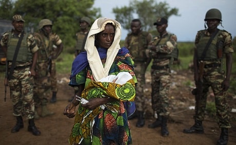 Un groupe de soldats autour d'une femme qui tient son bébé.