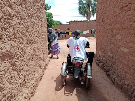 Bénévole de la Croix-Rouge malienne, portant un dossard blanc, sur une moto