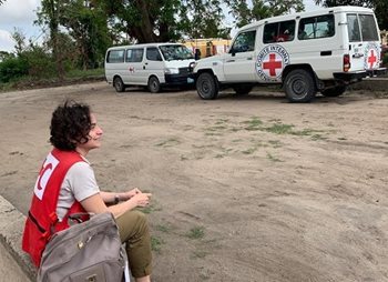 Lucia est assise sur le sol face à des voitures de la Croix-Rouge