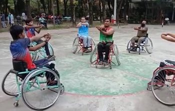 Des personnes en chaise roulante font des étirements sur un terrain de basketball