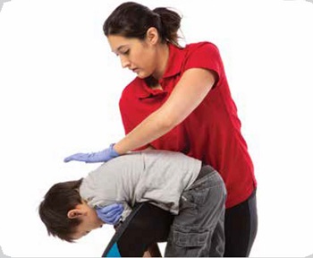 Une femme portant un chandail rouge fait une manoeuvre pour aider un enfant qui s'étouffe en lui tapant dans le dos