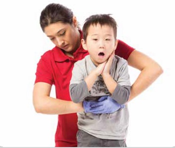 Une femme portant un chandail rouge fait une manoeuvre pour aider un enfant qui s'étouffe en faisant des poussées abdominales