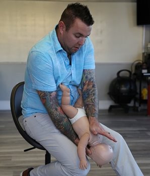 Kyle Mohler, de LifeShield First Aid, fait une démonstration de la technique de premiers secours assis pour l'étouffement d'un nourrisson.