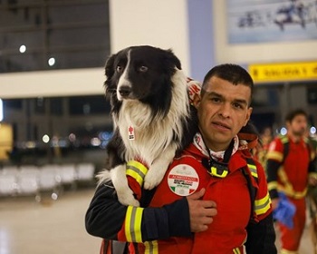Un homme portant un uniforme rouge tient un chien sur son épaule
