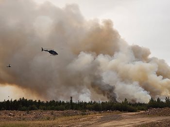 Un ciel avec de la fumée des feux de forêt et un hélicoptère