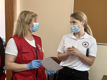 Deux femmes vêtues de vestes de la Croix-Rouge discutent