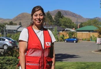 Zaineb souriant dans un gilet de la Croix-Rouge avec des montagnes en arrière-plan.