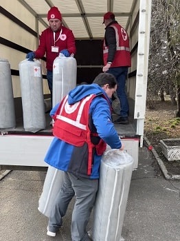 Des membres du personnel de la Croix-Rouge livrent des matelas au centre communautaire abritant des personnes déplacées à l’intérieur du pays à Geronymivka.