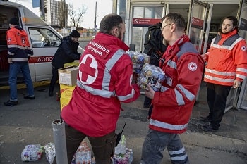 Des personnes portant des vestes de la Croix-Rouge transportant des caisses de bouteilles d'eau, distribuant de la nourriture aux personnes réfugiées dans les stations de métro pendant les bombardements.