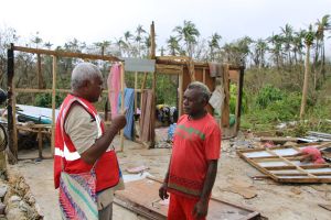 Deux hommes discutent devant des débris causés par le passage d’un cyclone.