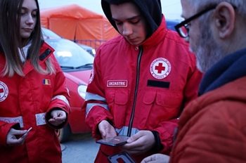Les membres de l'équipe de la Croix-Rouge roumaine réunis autour de leur téléphone
