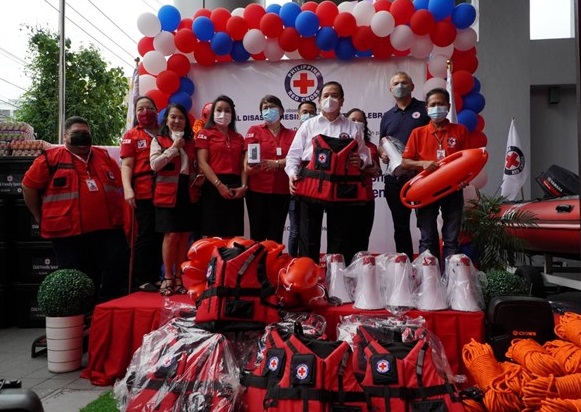 Des membres de la Croix-Rouge philippine posent pour des photos sur une scène, avec le matériel d'intervention d'urgence exposé.