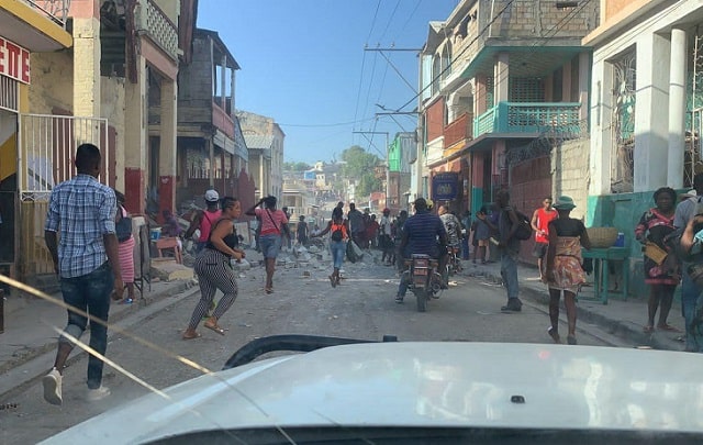 Des gens courent dans une rue en ruines après le tremblement de terre.