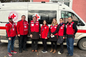 Des membres du personnel de la Croix-Rouge prennent la pose pour une photo devant une unité de santé mobile.