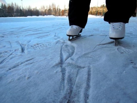 Deux pieds portant des patins blancs, sur une patinoire
