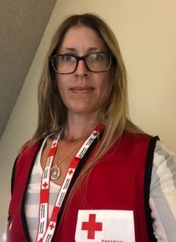 Une femme avec des lunettes et un gilet de la Croix-Rouge canadienne.