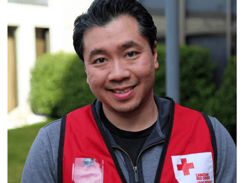 Un homme souriant portant une veste rouge de la Croix-Rouge