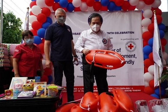 Des membres de la Croix-Rouge philippine sont sur scène, tandis que l'un d'eux brandit une trousse d'urgence lors d’une cérémonie.