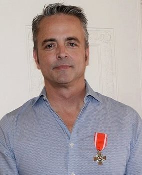 Une photo de tête d'un homme portant la médaille de l'Ordre de la Croix-Rouge