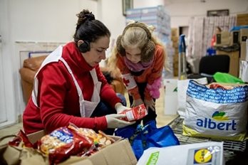 Une femme et une jeune fille dans une salle d'approvisionnement devant une boîte ouverte remplie de nourriture