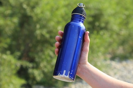 Une main qui tient une bouteille d'eau bleue en métal