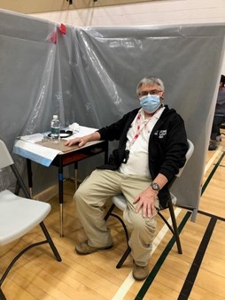 George Rudanycz est assis dans un centre de vaccination avec son masque