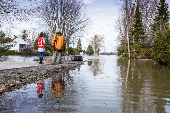 A Canadian Red Cross emergency responder and a man survey flood damage.