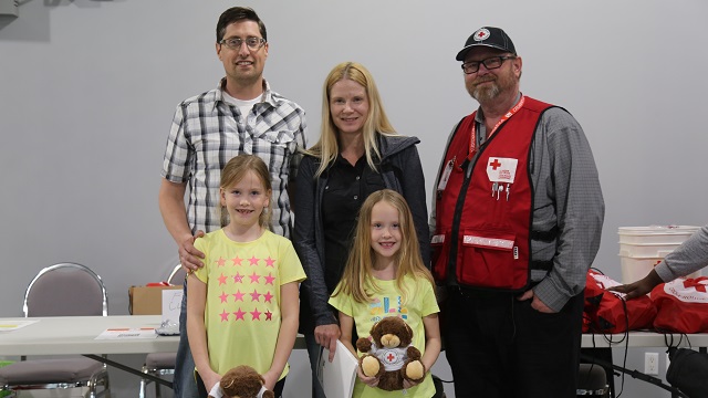 Une famille à côté d'un homme du CRC dans un centre de lutte contre les incendies de l'Alberta