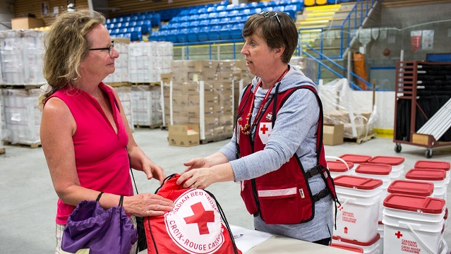 Une bénévole de la Croix-Rouge canadienne remettant un sac à un évacué en Colombie-Britannique. 