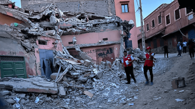 Membres du Croissant Rouge marrocain à côté d'une maison détruite par le tremblement de terre 