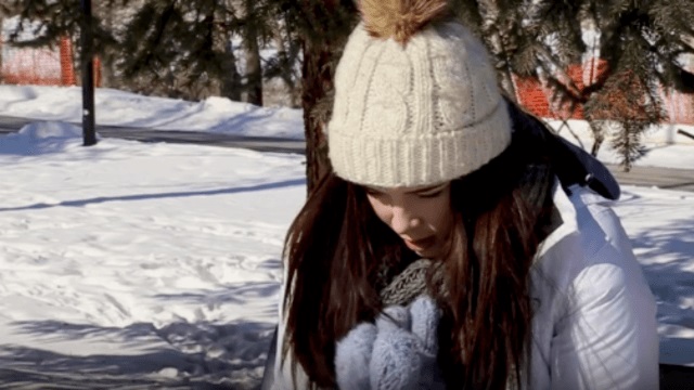 Une jeune fille assise dehors dans le froid en se frottant les mains pour se réchauffer