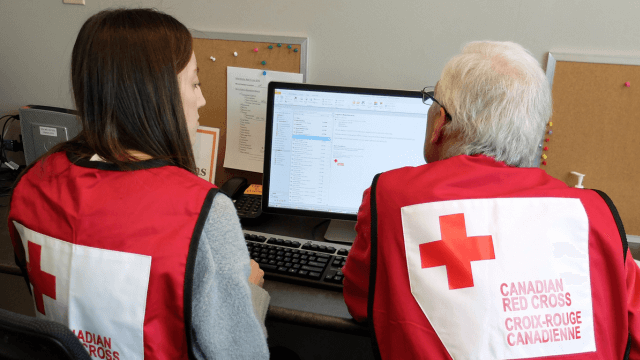Deux members de la Croix-Rouge canadienne travaillant à l'aide d'un ordinateur